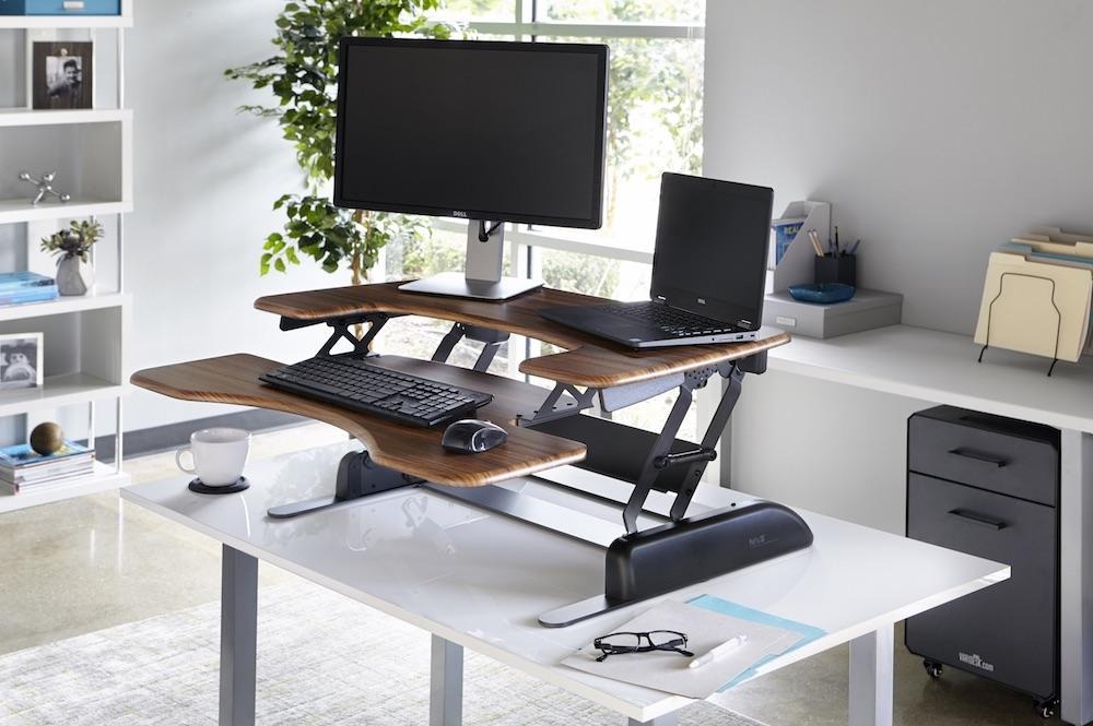 A bright home workspace with a desk, monitor and laptop